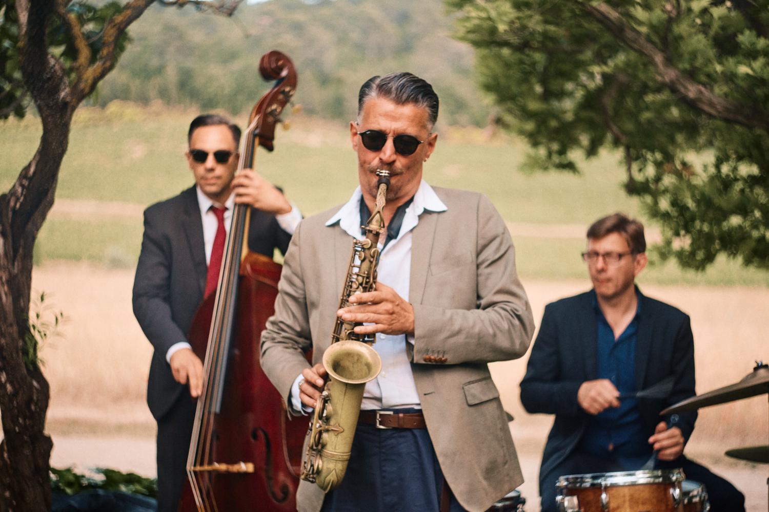 A saxophone player performs outdoors with band at Chateau Val Joanis