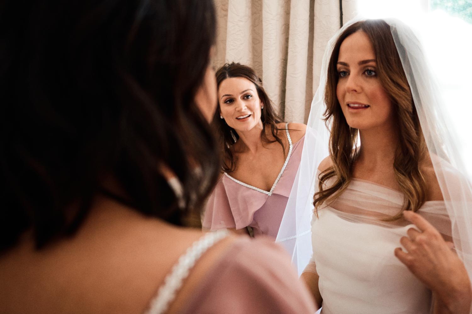 Two bridesmaids look at a bride