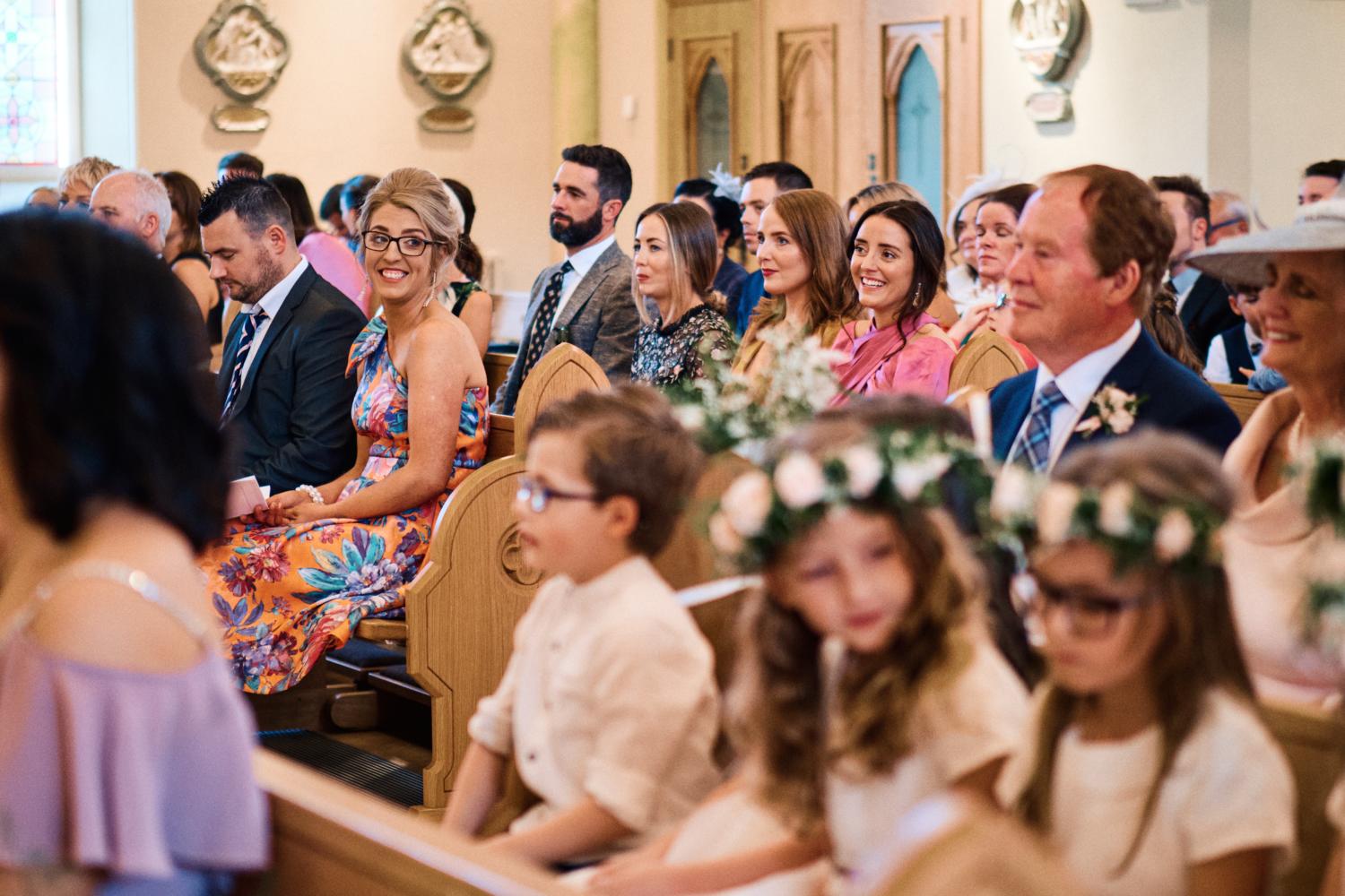 Wedding guests smiling at a Catholic wedding mass