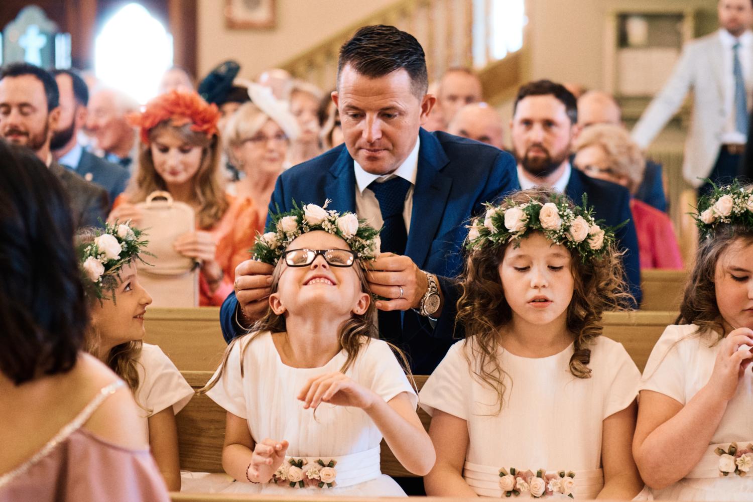 A father helps fix a child's floral head piece