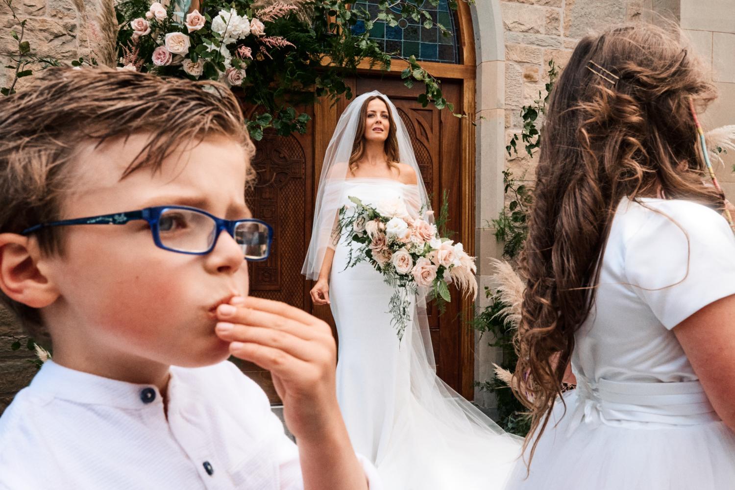 Children eating crisps in front of a bride outside a church