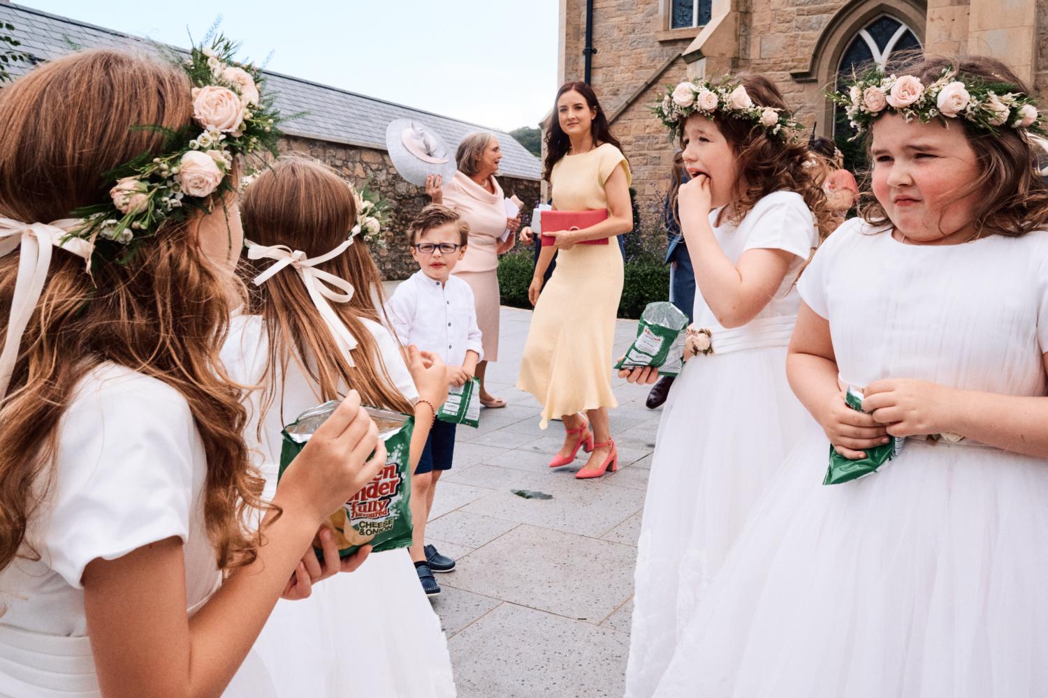Flower girls eat crisps at a wedding