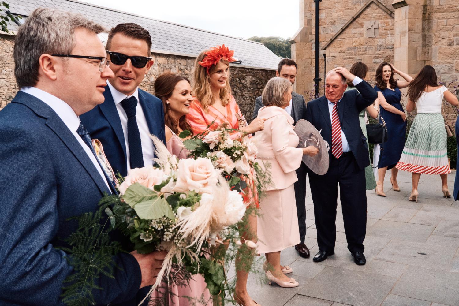 Wedding guests holding flowers outside a chapel
