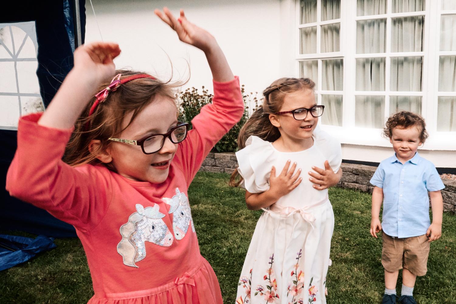Three children dance at a wedding garden reception