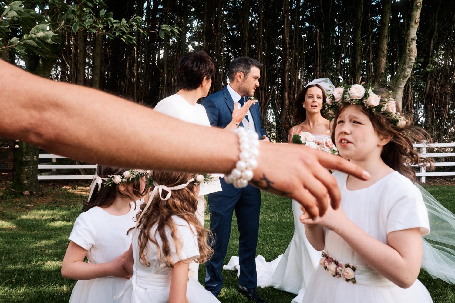 A mother points at a flower girl at a wedding