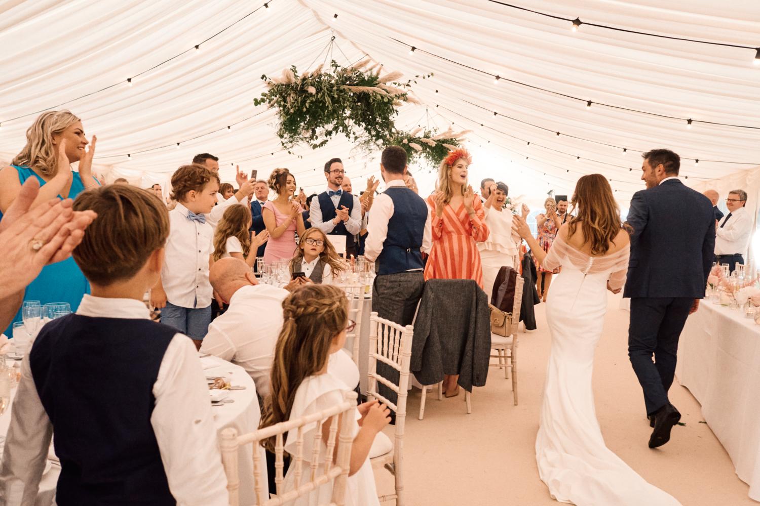Guests celebrate the arrival of the newly wedded couple in a marquee