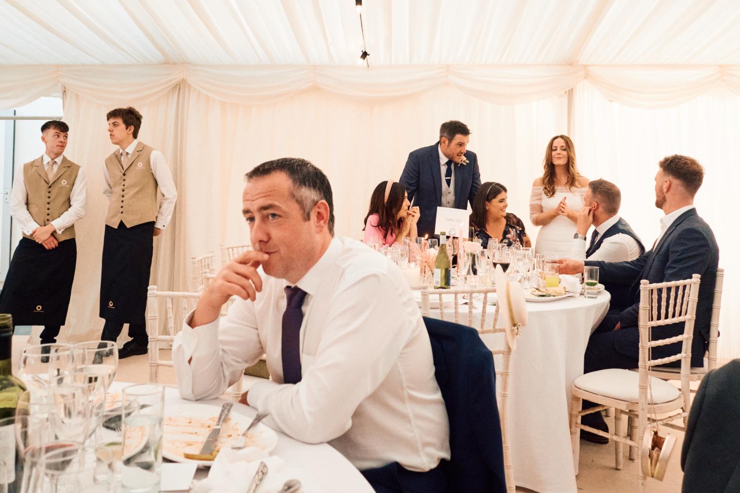 Wedding guests mingle in a marquee in the evening