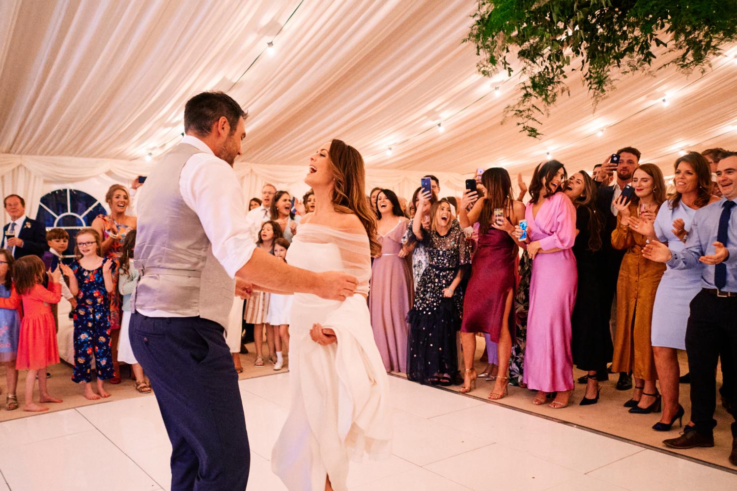 A bride and groom begin their first dance in a marquee