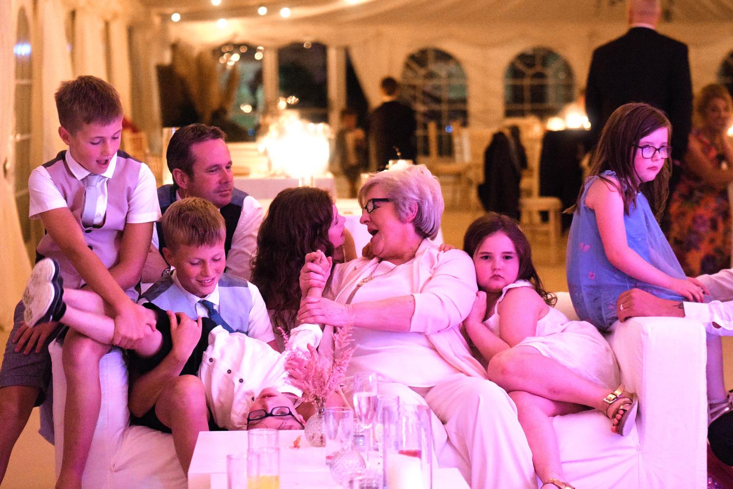 A grandmother plays with her grandchildren at a wedding