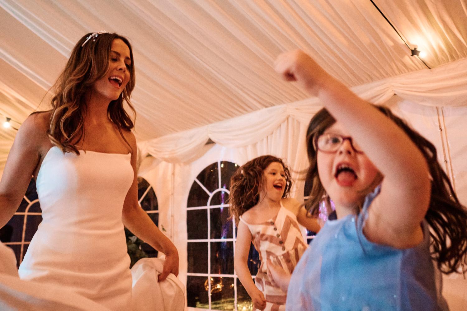 A bride dances with funny children at a wedding