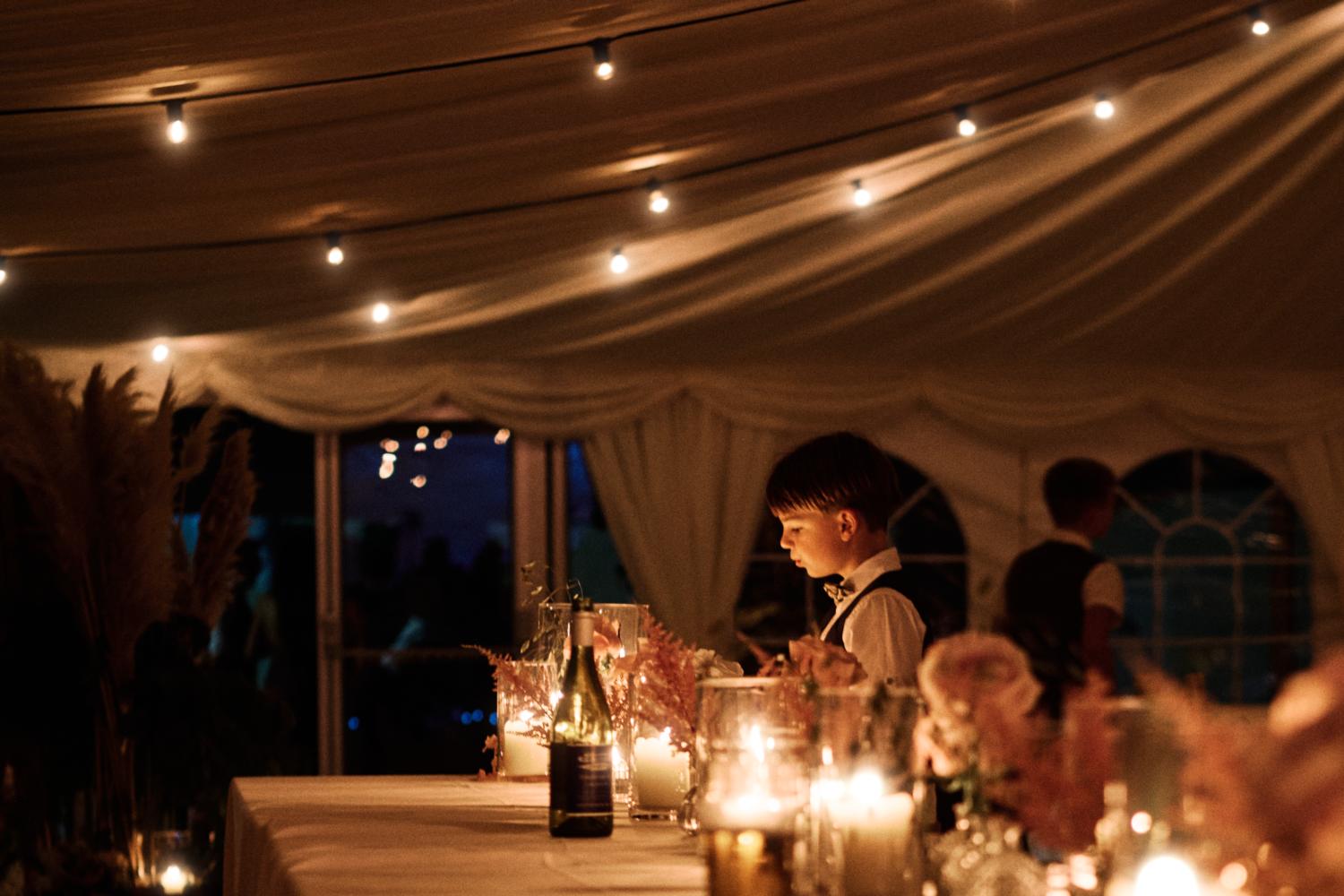 A child plays with candlelight at a marquee wedding