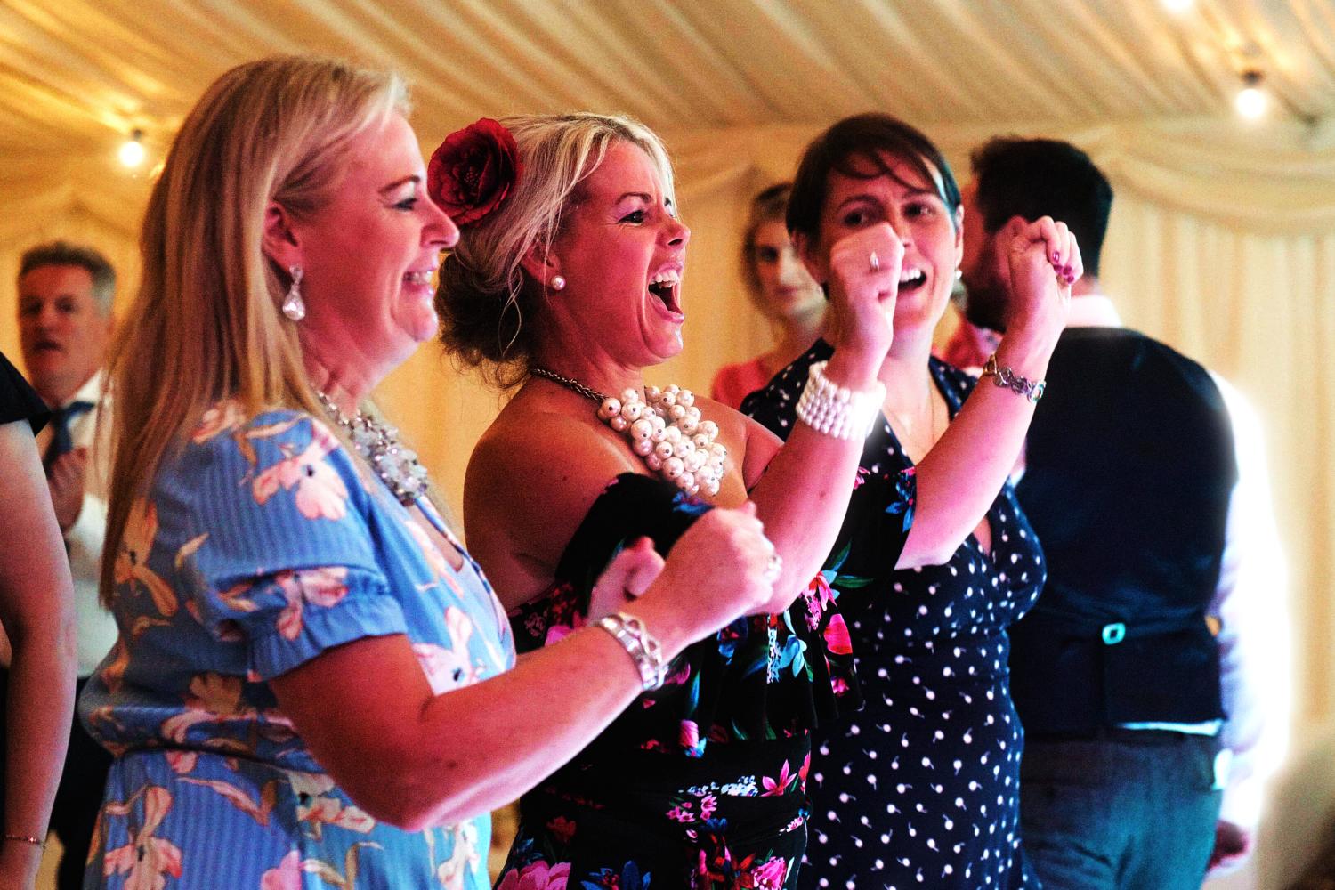 Three women singing at a wedding