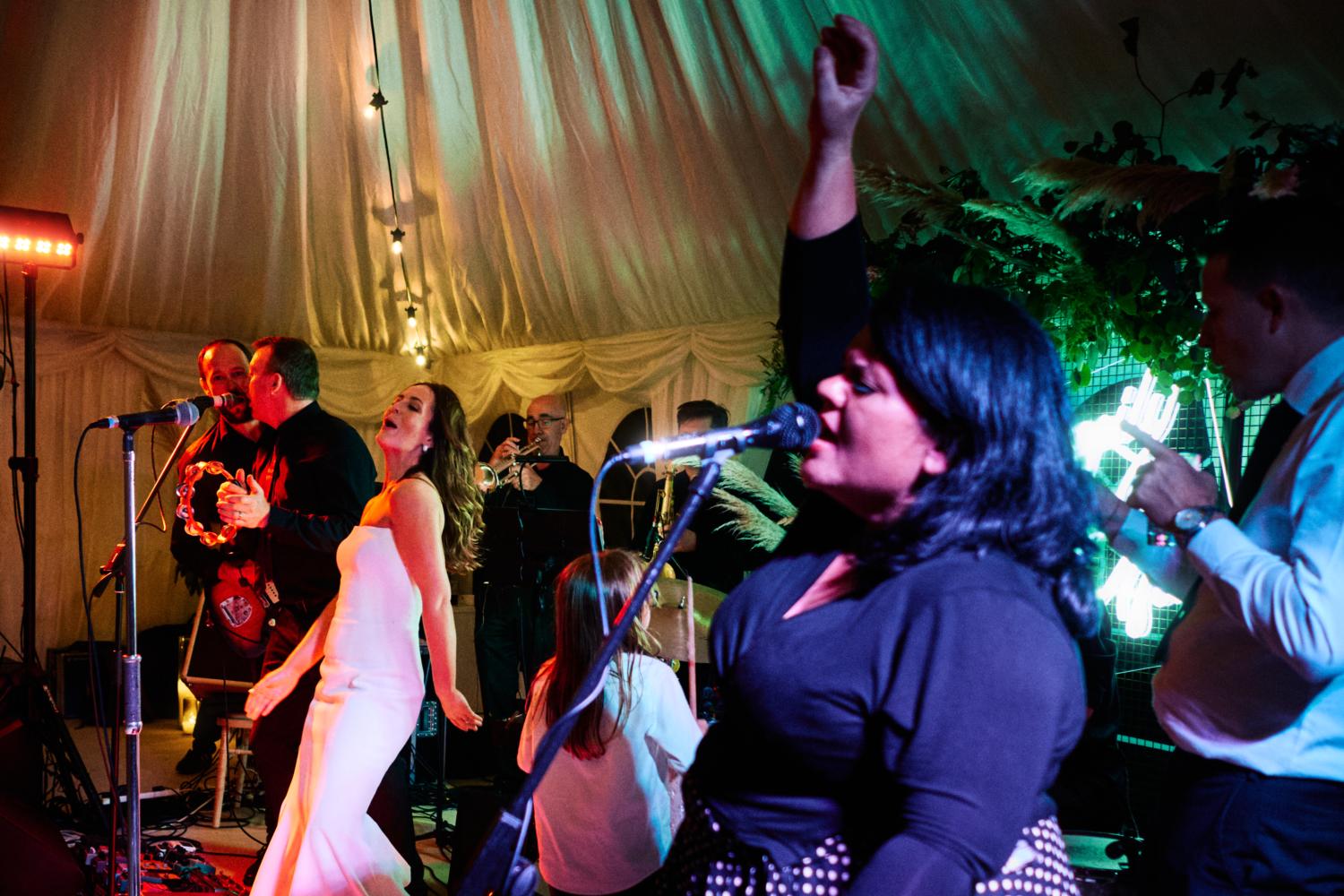 A bride sings with the wedding band in a marquee
