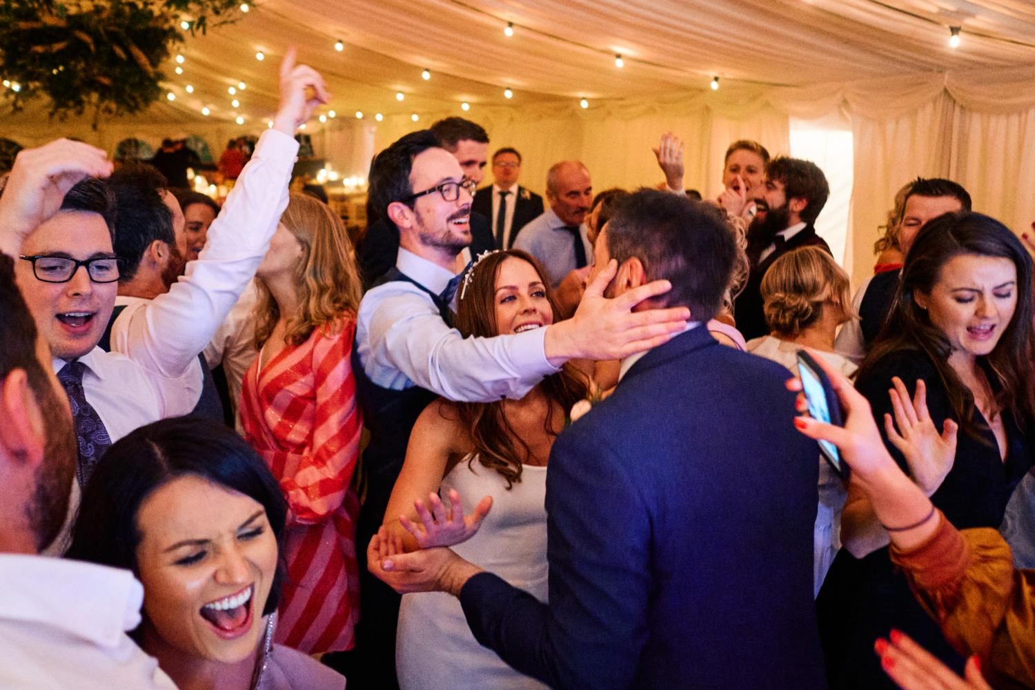 Wedding guests embrace the bride and groom at a wedding