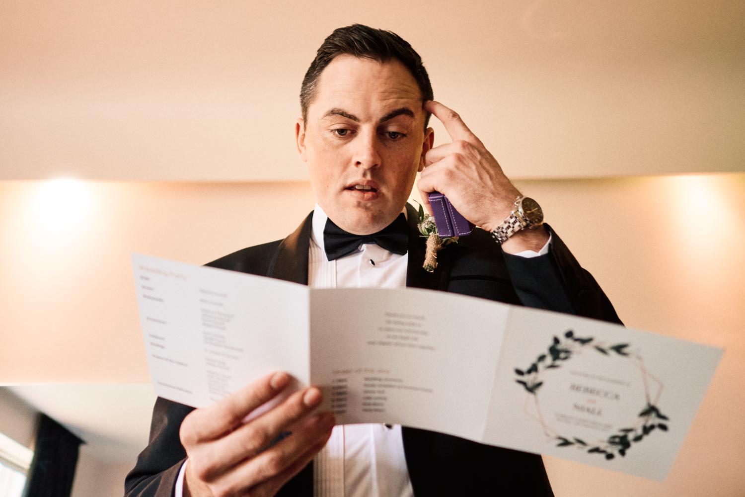 An Irish groom reads wedding service in a tuxedo