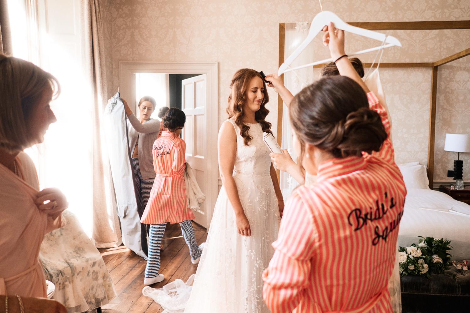A bride tries on a wedding dress surrounded by her bridal party