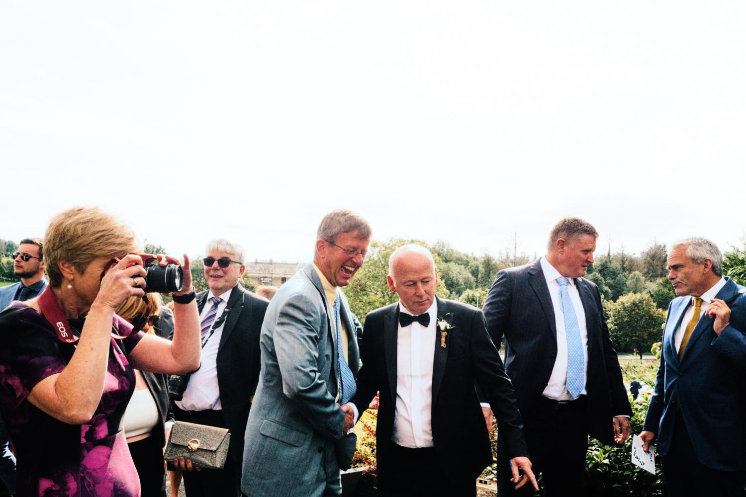 Wedding guests greet each other and take photographs at a wedding