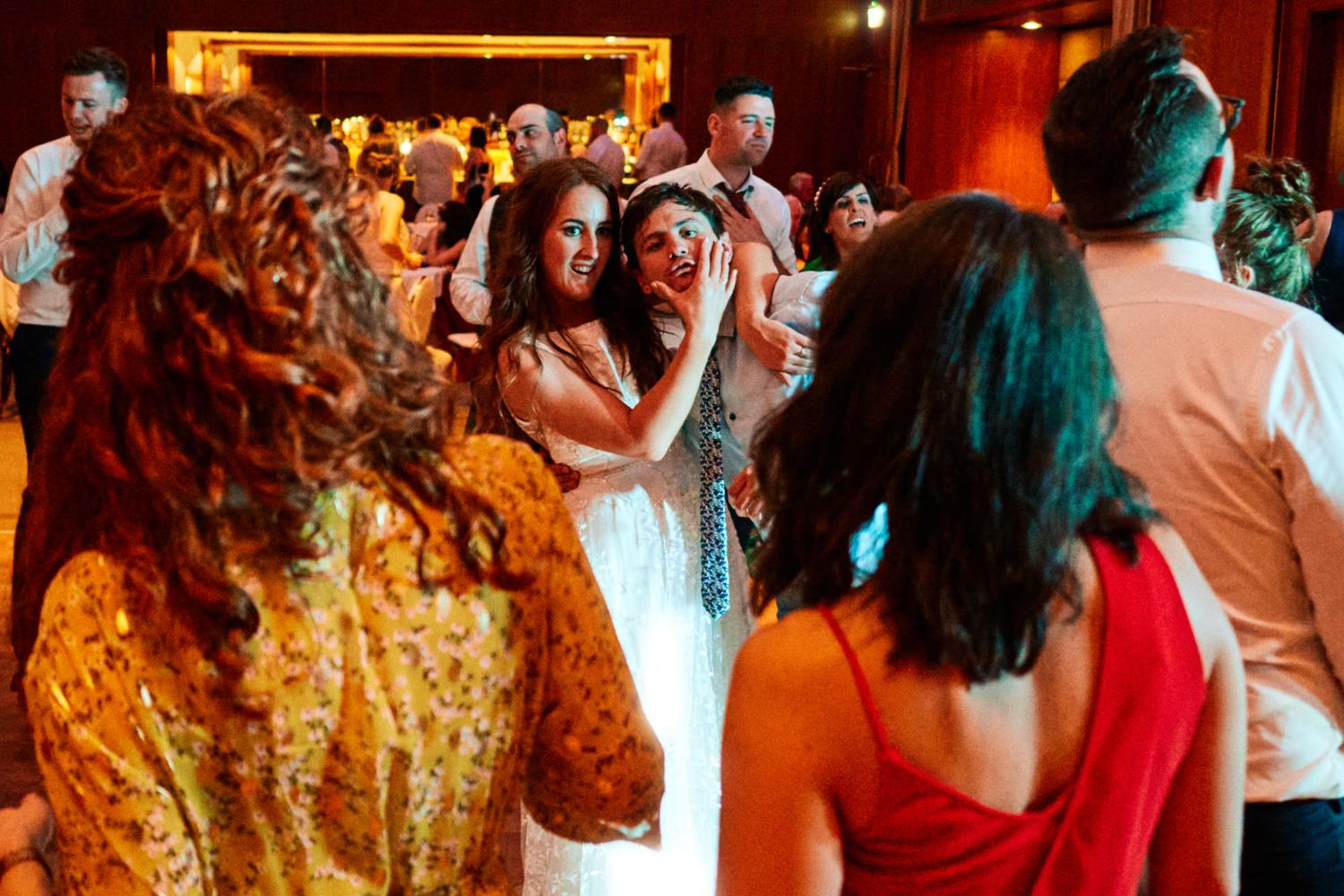 Bride squeezes friend's face on dance floor