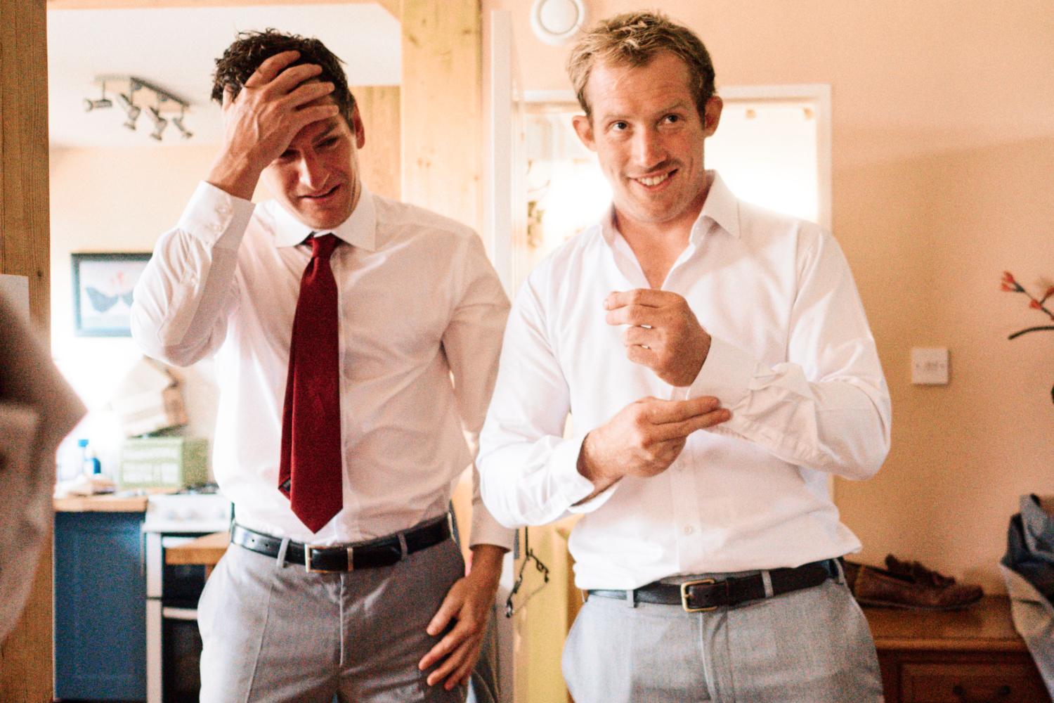 A groom fixes his cuff links with his friend