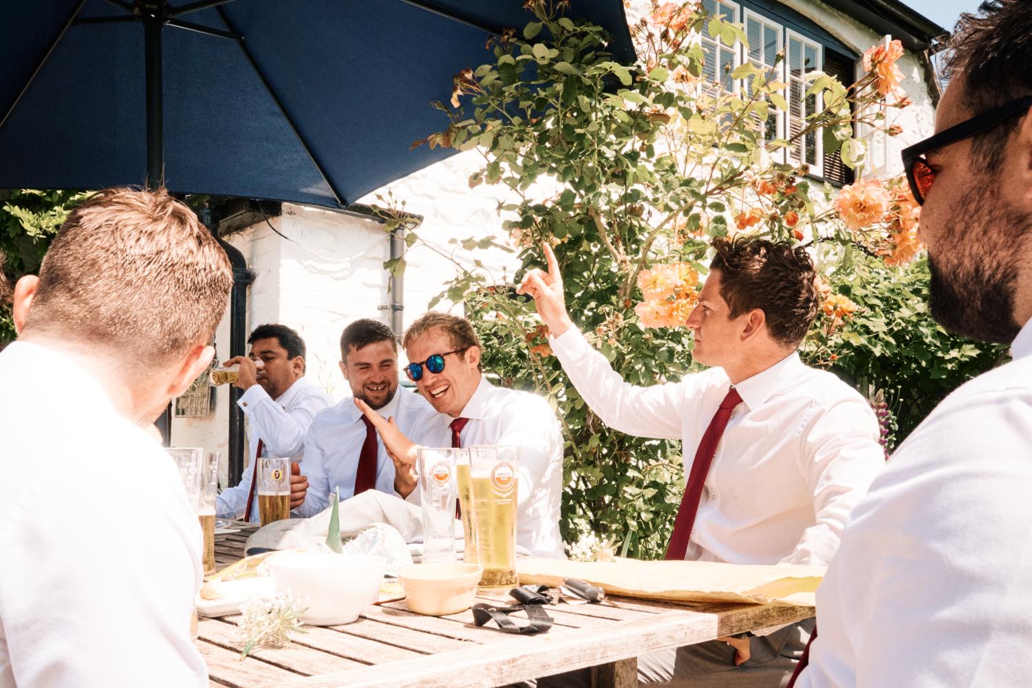 Groom and friends drink and laugh in the sun