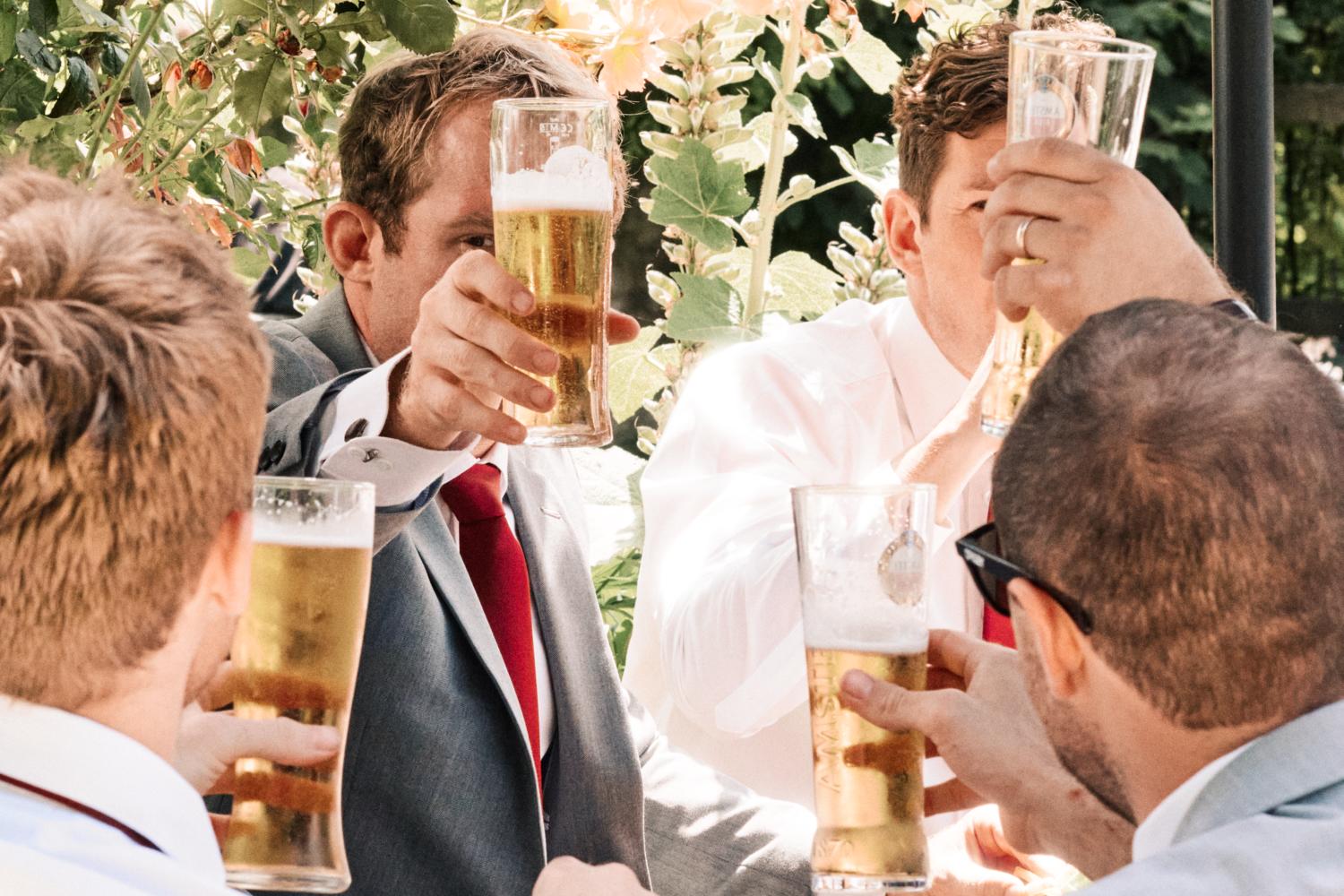 Groomsmen lift pints of beer in the air