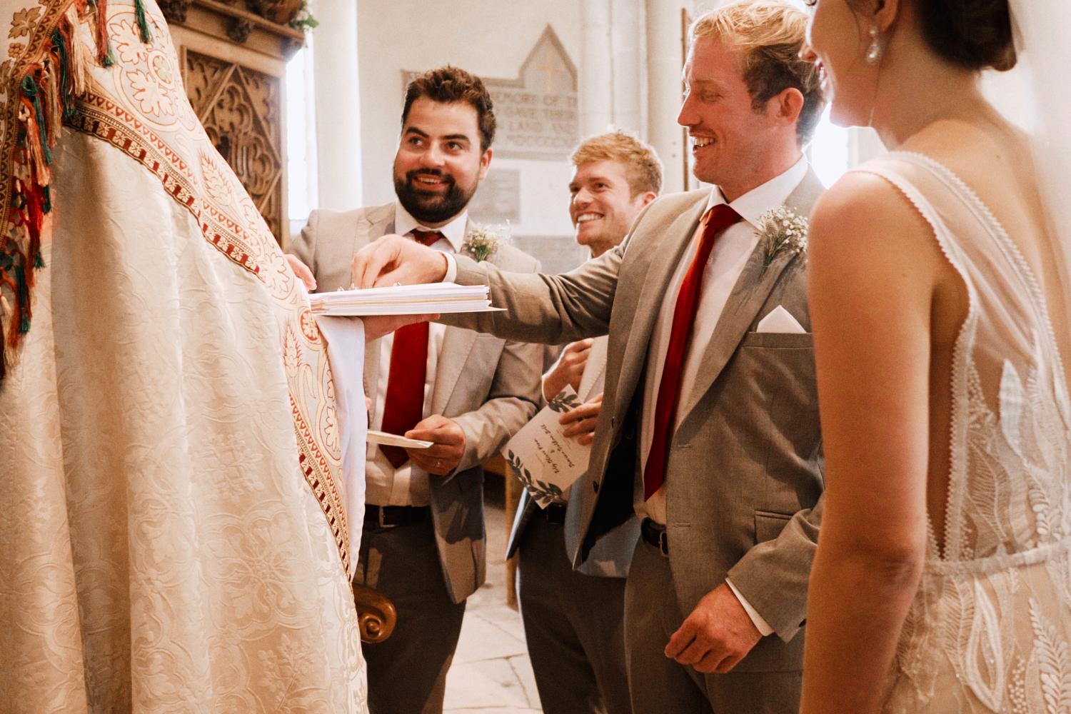 A groom reaches for rings during the vows