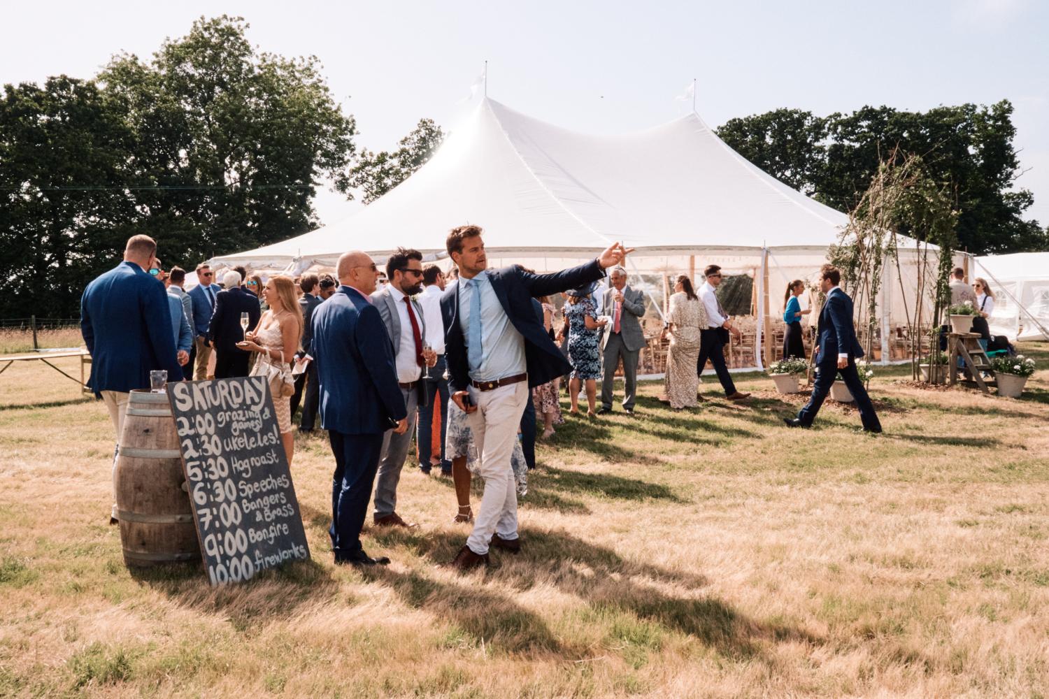 Guests mingle outside a marquee in a field
