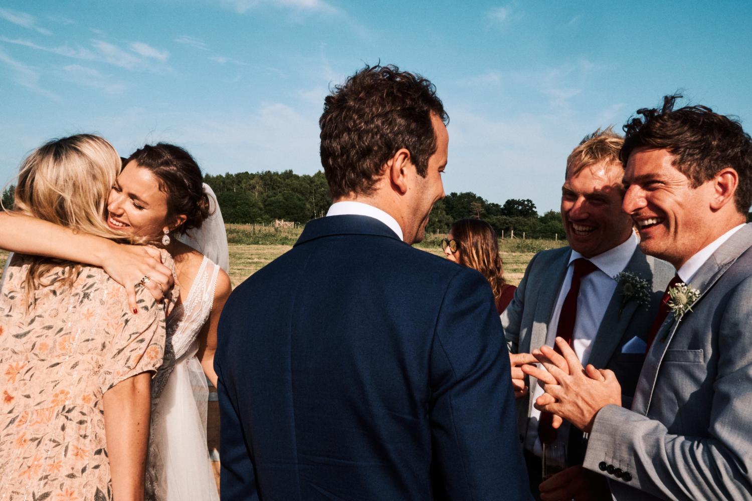 A bride hugs a friend at an outdoor wedding reception in Ewelme