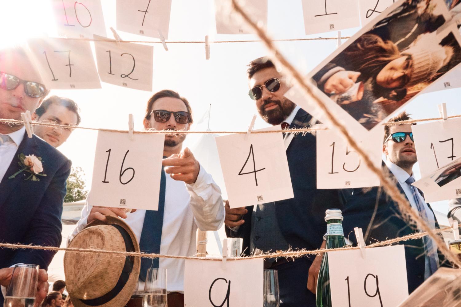 Men in sunglasses look at a picture display with numbers