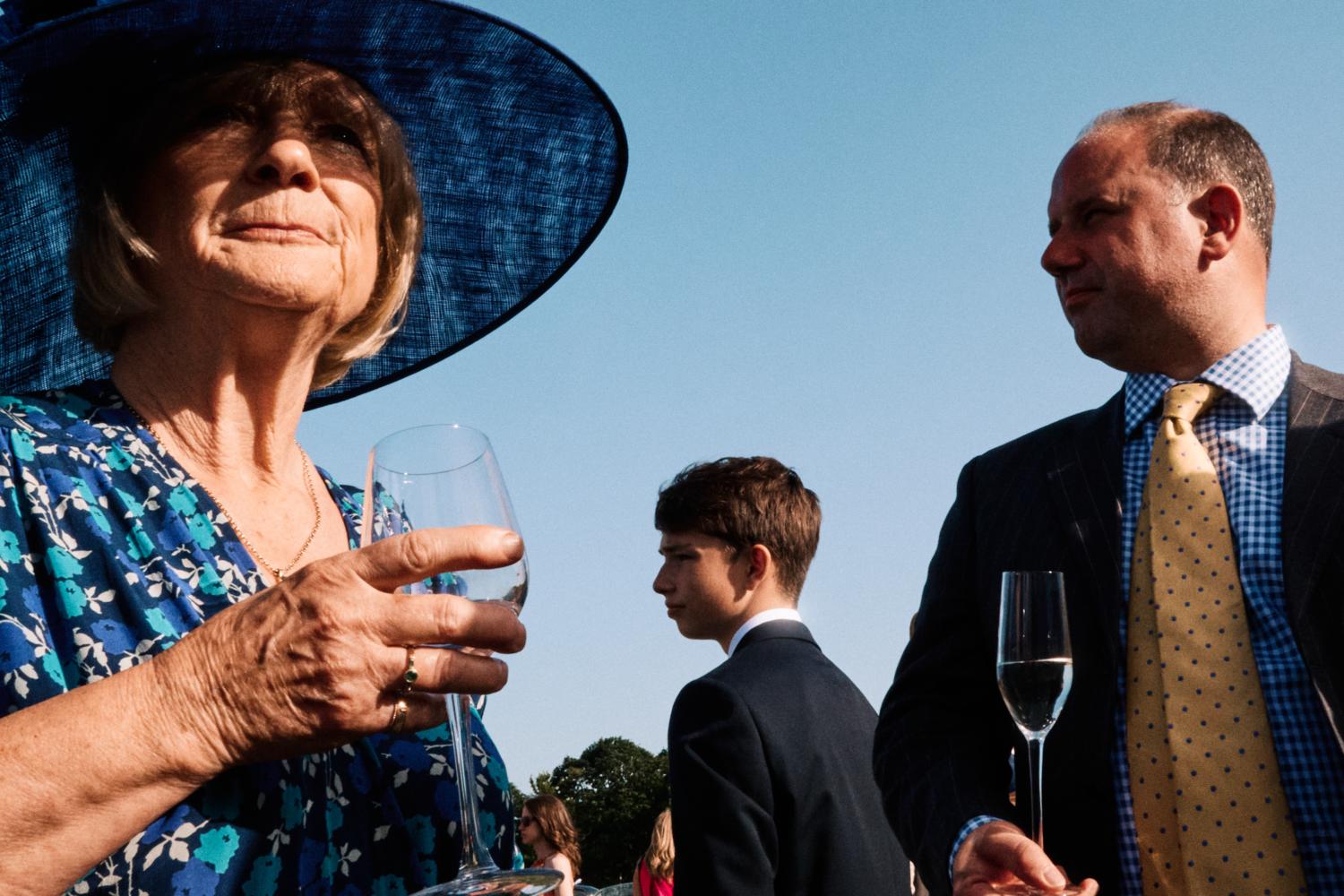 Three wedding guests look in separate directions at a wedding