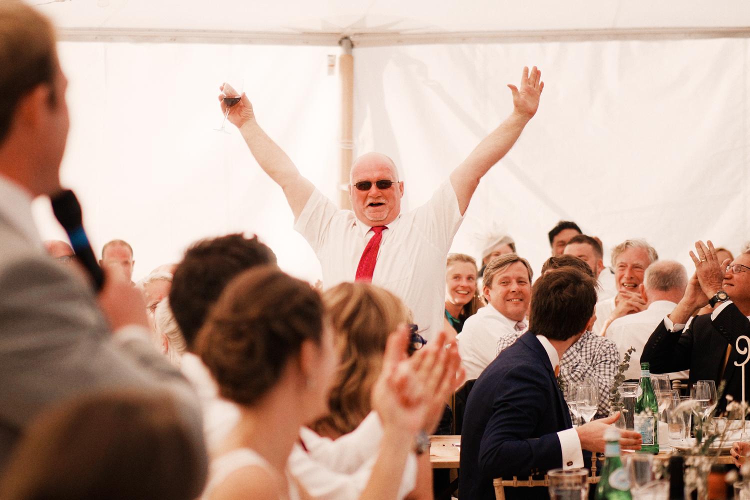 Father of the groom raises his hands dramatically during the speeches