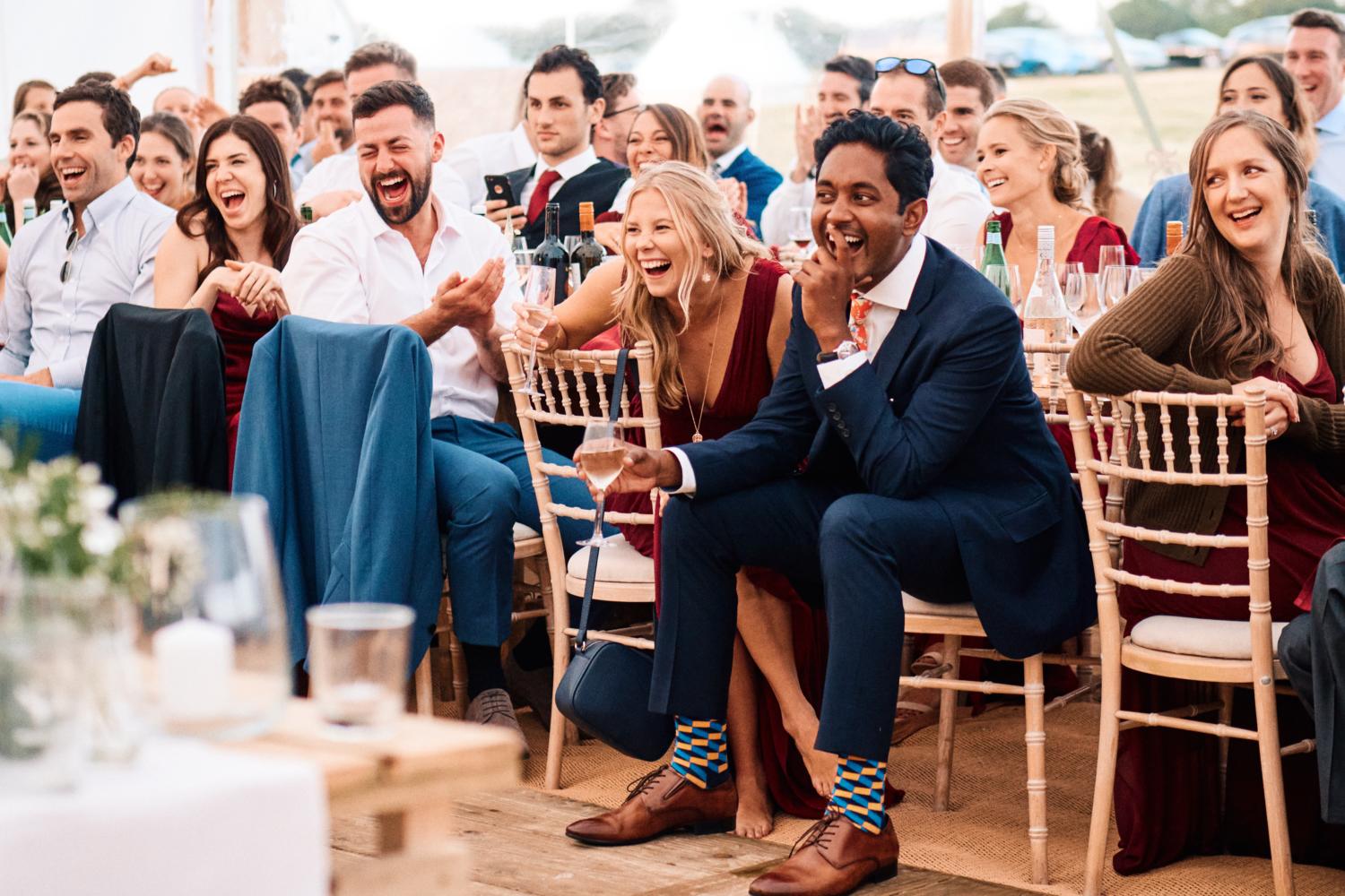 Wedding guests laughing during speeches in a marquee