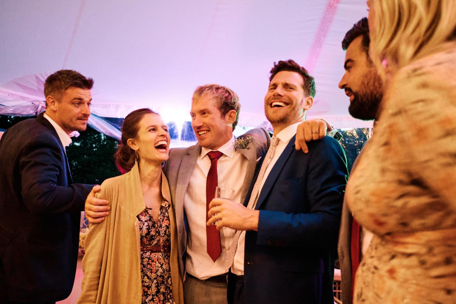 A groom holds his friends in a marquee