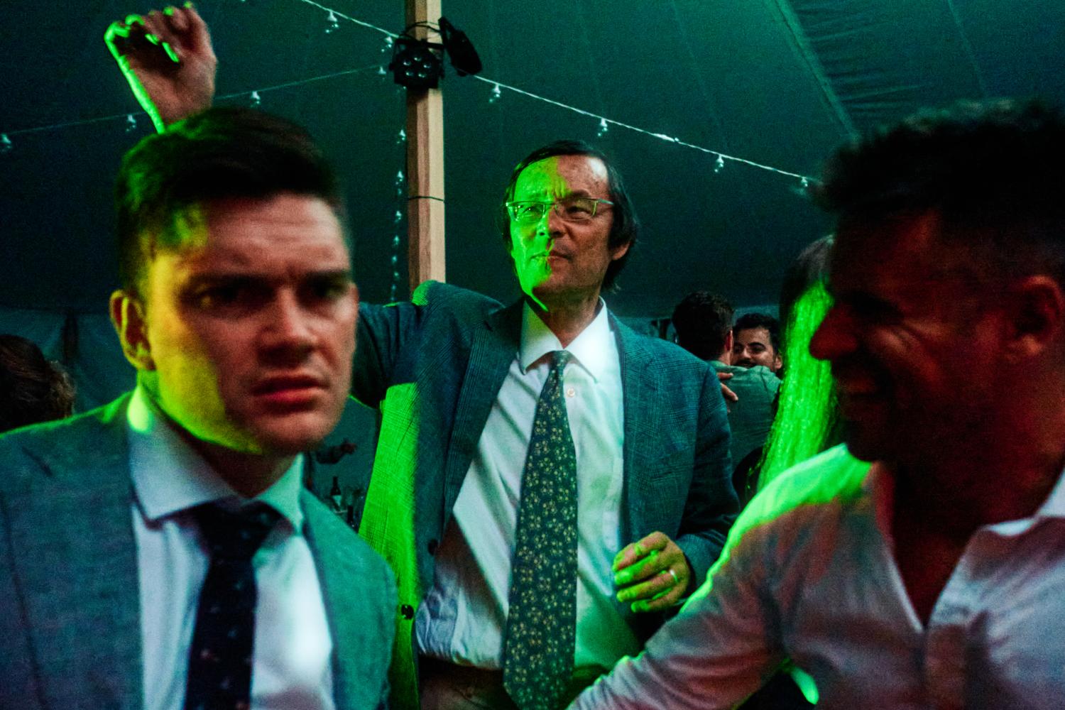 Three men dance in green light