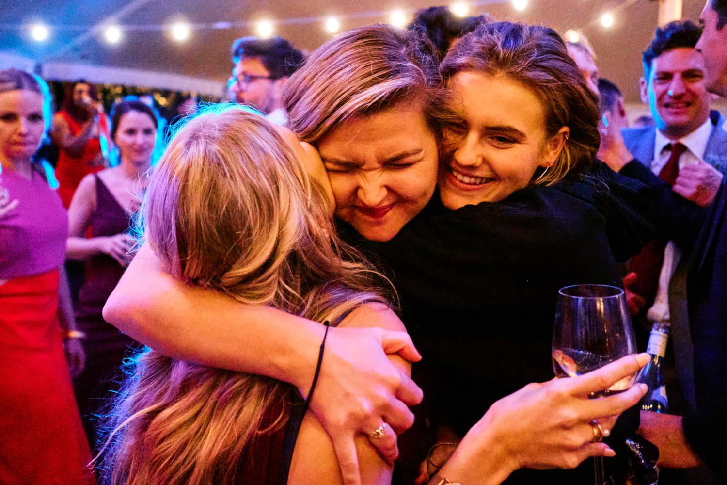Sister of the bride hugs her friends in a marquee