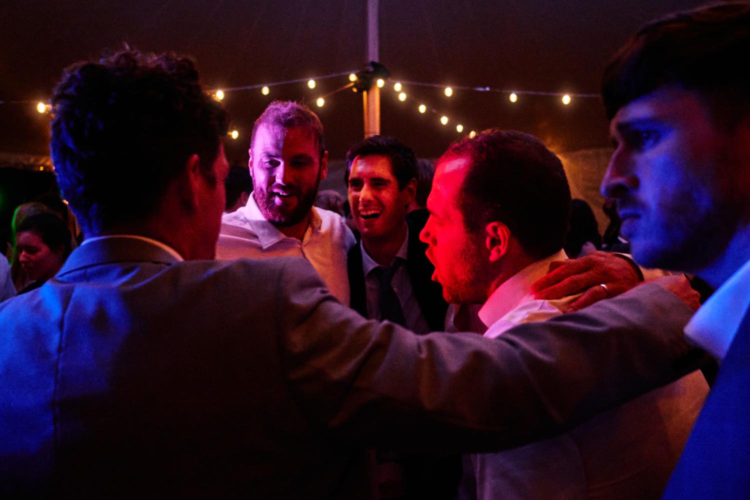 Men dance together in a marquee